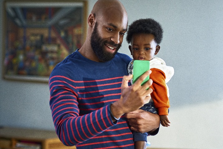 Photo of a man holding a small child and talking on the phone
